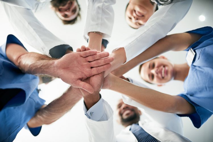 Shot of a diverse team of doctors joining their hands together in unity